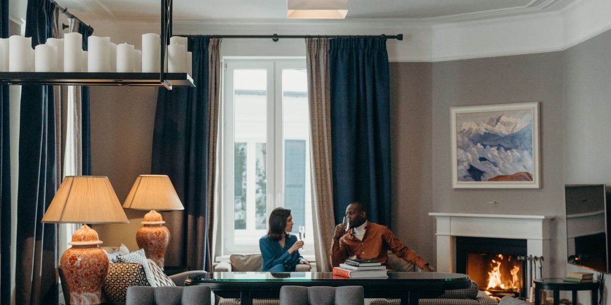 An elegant couple sits on a luxurious sofa, reviewing property brochures, imagining their future home.