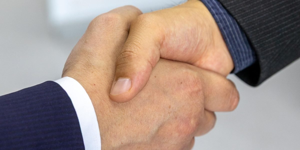 Two professionals shaking hands, symbolizing the successful negotiation and closing of a high-value real estate deal.
