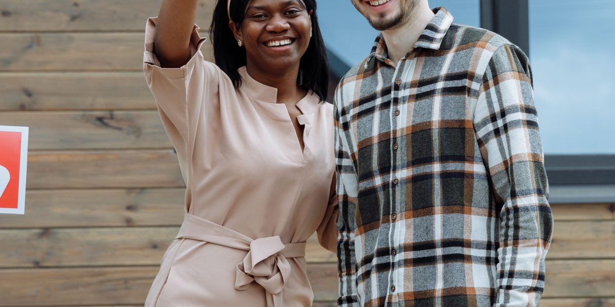 A joyful couple celebrating their new home, holding keys, representing the successful outcome of their property journey.