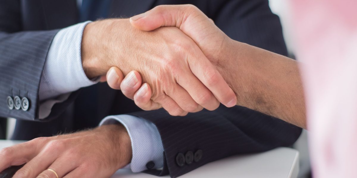 Professionals shaking hands after reaching a mutually beneficial agreement in a real estate transaction.